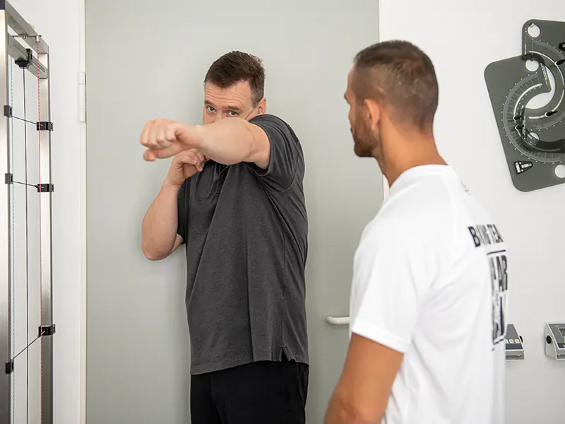 Chiropraktiker demonstriert einem Boxer eine Schlagbewegung